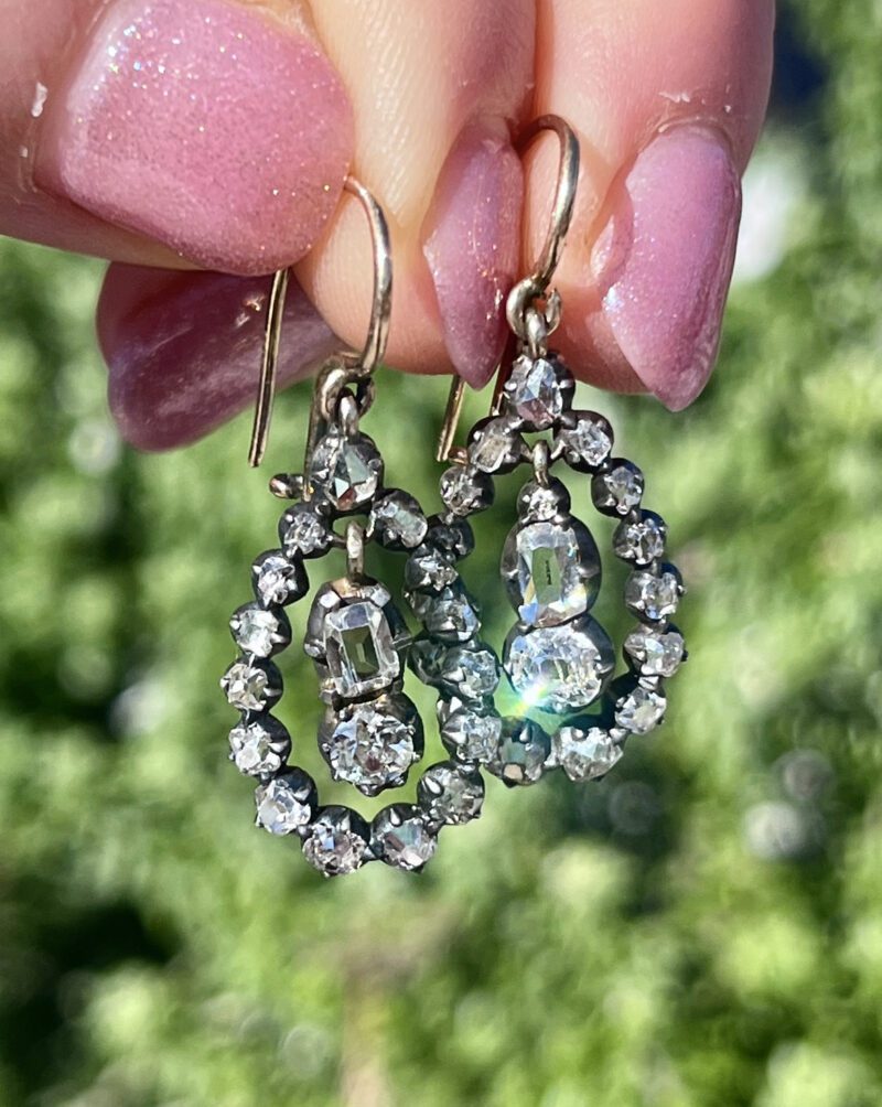 Diamond earrings held by pink nails.