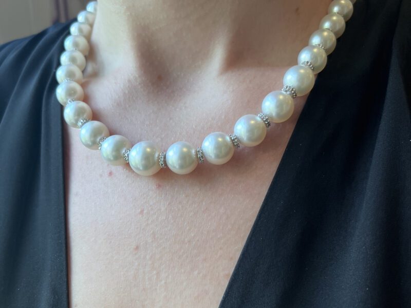 Pearl necklace on person wearing black top.