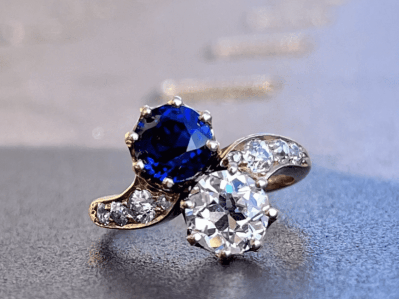 A blue and white diamond ring on top of a table.