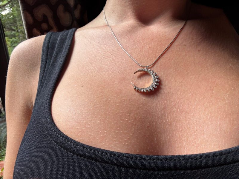 Necklace with crescent pendant on woman's chest.