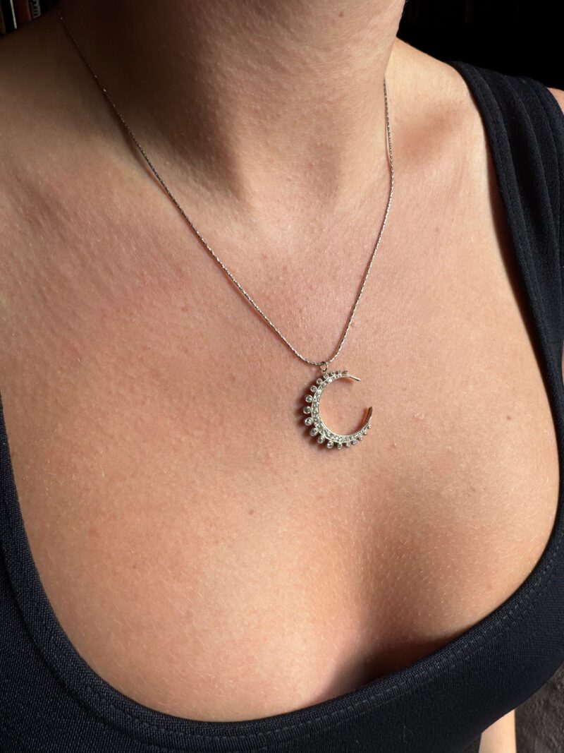 Necklace with crescent moon pendant on woman.