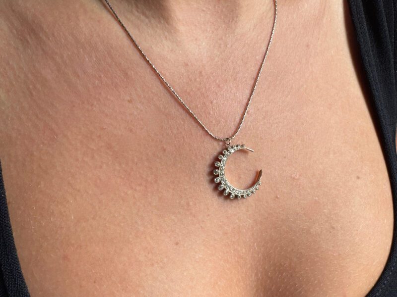 Necklace with crescent moon pendant on woman.