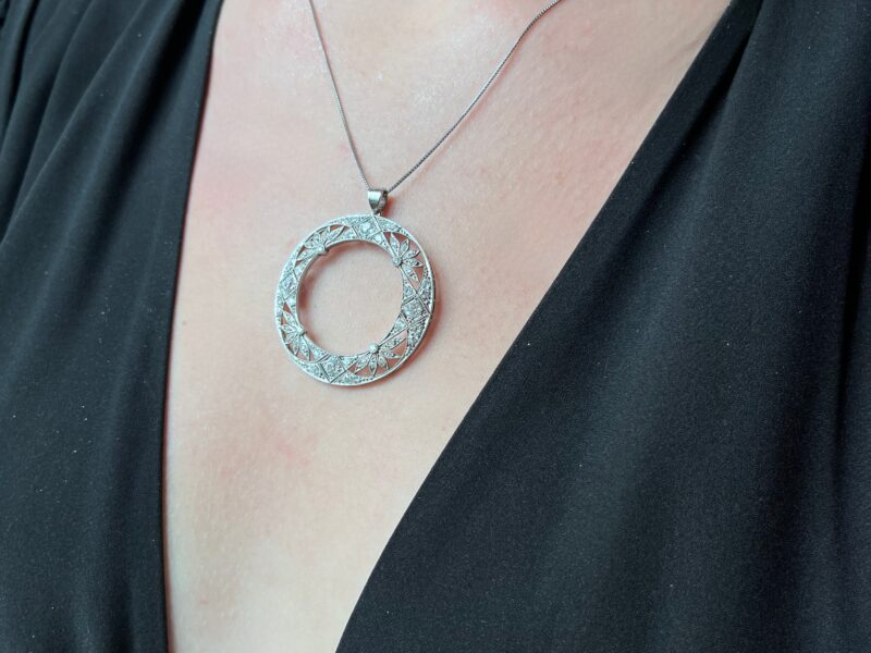 Necklace with circular pendant on black dress.