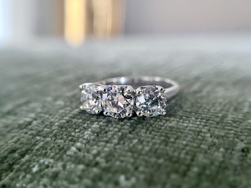 Three-stone diamond ring on green fabric.